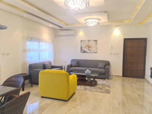 a living room with two couches and a yellow chair at Khalda Rooftop Apt. in Amman