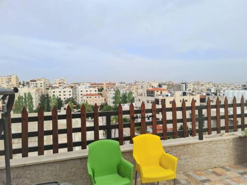 two chairs sitting on a fence with a view of a city at Khalda Rooftop Apt. in Amman