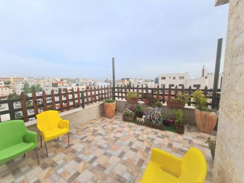 a balcony with yellow and green chairs on a building at Khalda Rooftop Apt. in Amman