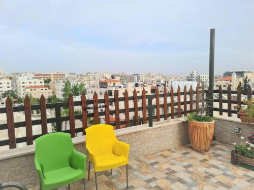 two green and yellow chairs sitting on a balcony at Khalda Rooftop Apt. in Amman