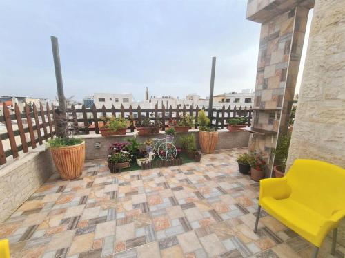 a patio with potted plants and a yellow chair at Khalda Rooftop Apt. in Amman