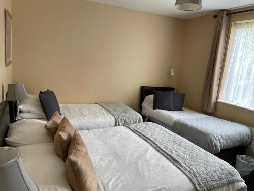 a room with three beds and a window at Fountain House B&B in Macroom