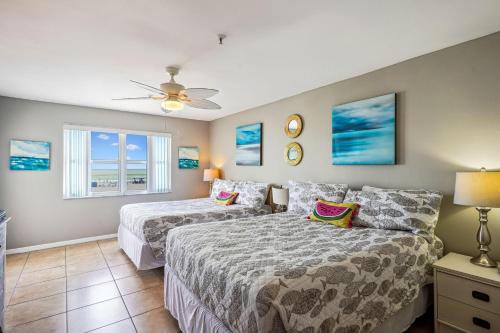 een slaapkamer met 2 bedden en een plafondventilator bij Sea Breeze 106 in St Pete Beach