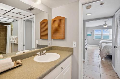 a bathroom with a sink and a bedroom at Sea Breeze 106 in St. Pete Beach