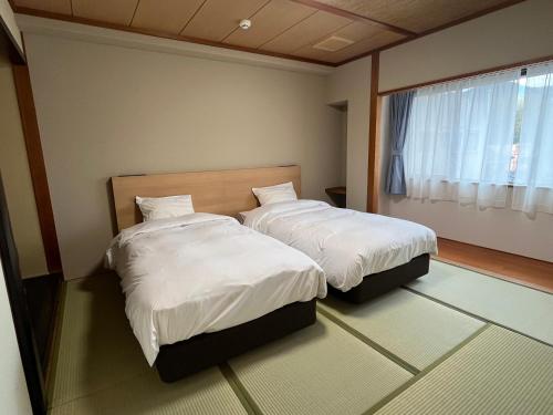 een slaapkamer met 2 bedden en een raam bij Ureshino Onsen Yusyuku Sarayama in Ureshino