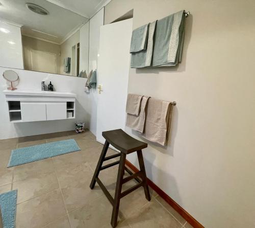ein Badezimmer mit einem Hocker vor einem Waschbecken in der Unterkunft Lakeview Cottage: Rural Retreat in Pampoenkraal