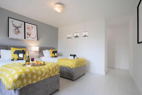 a bedroom with two beds with yellow and white sheets at Stylish 6 Bedroom 3 Bathroom Detached House with Free Parking, Super-Fast Wifi, Pool Table, Smart TVs with Netflix by Yoko Property in Milton Keynes