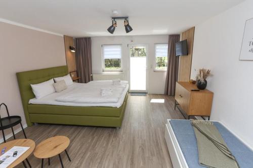 Falk & Frei Selketal Resort في Meisdorf: غرفة نوم بسرير اخضر وطاولة وكراسي