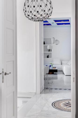 a white living room with a white couch and a chandelier at White Loft Syros in Ermoupoli