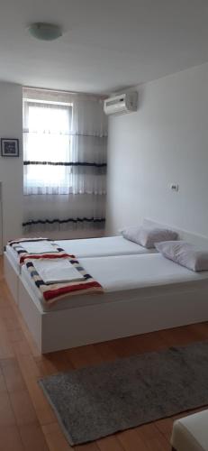 uma grande cama branca num quarto com uma janela em Apartmani M em Mostar