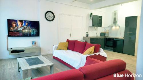 - un salon avec un canapé rouge et une horloge murale dans l'établissement Le Nautilus - Plage et Kursaal, à Dunkerque