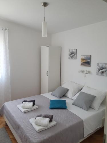 a large white bed with two towels on it at Apartmani Kunteja in Pag