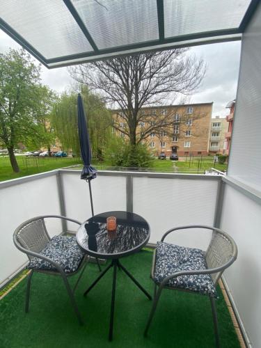 eine Terrasse mit 2 Stühlen, einem Tisch und einem Sonnenschirm in der Unterkunft Diana Apartments 2 in Bardejov