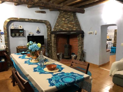 ein Esszimmer mit einem Tisch und einem Kamin in der Unterkunft Casal dos Carpinteiros - Carpenters Couple in Silveira