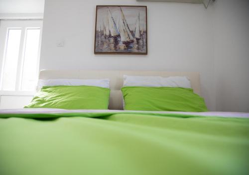 a bed with two green pillows and a painting at Apartment Dapcevic Skadar lake in Vranjina