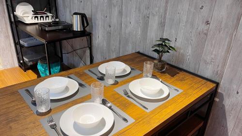 een houten tafel met witte borden en bestek erop bij S1 Cozy Home Sunway Geo 2Queens Sunway Medical Centre in Petaling Jaya