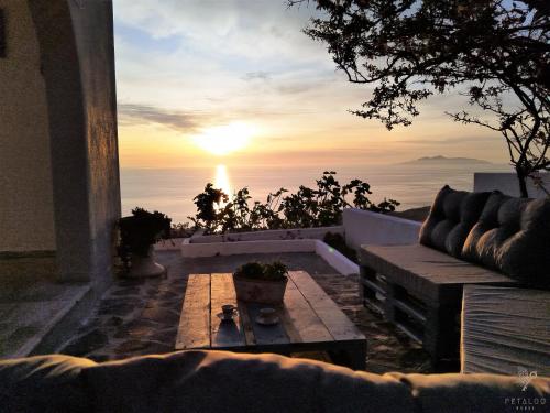 a sunset from the balcony of a house with a couch at Petalou House in Imerovigli
