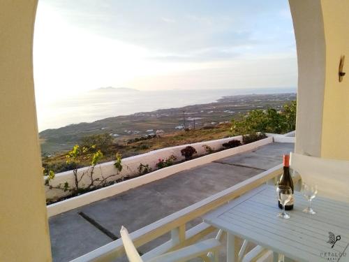 a view from the balcony of a house with a table and wine bottle at Petalou House in Imerovigli