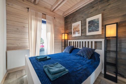 1 dormitorio con 1 cama azul y paredes de madera en Perle (Ferienhaus) an der polnischen Ostsee en Perlino
