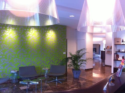 a waiting room with chairs and a green wall at Hotel Les Amandiers in Tournon-sur-Rhône