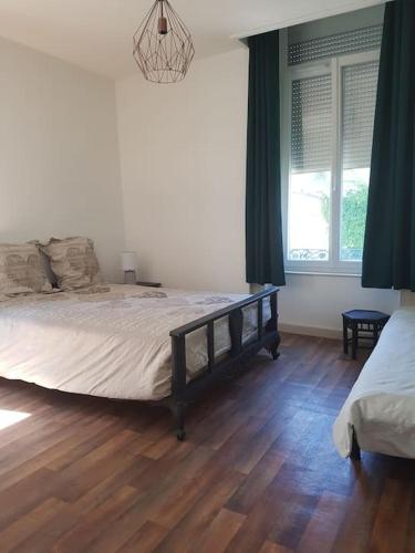 une chambre avec un grand lit et un parquet dans l'établissement Agréable appartement lumineux au centre-ville, à Oyonnax