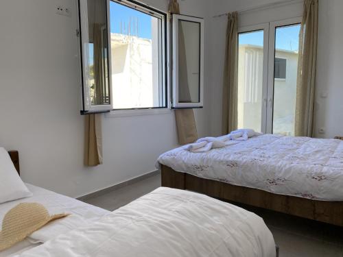 1 dormitorio con 2 camas y 2 ventanas en Orphanos House, en Kamilari