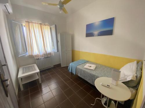 a small room with a bed and a table with a laptop at Alabe Hotel Marina di Tresnuraghes in Tresnuraghes