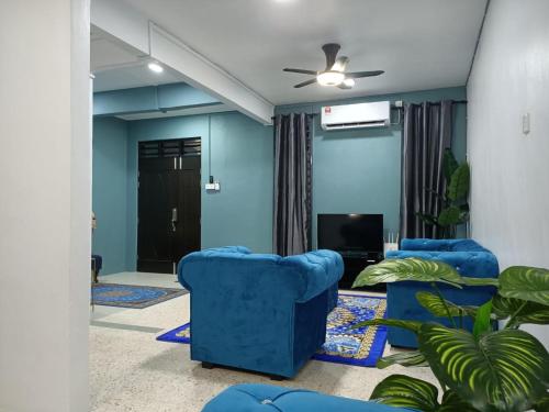 a living room with blue chairs and a television at RIANI HOMESTAY in Kertih