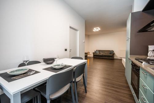 a kitchen and dining room with a white table and chairs at Appartamenti Vasco Renna Surf Center in Nago-Torbole