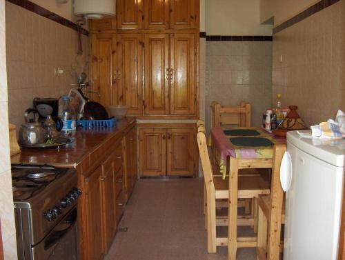 een keuken met houten kasten, een tafel en een fornuis bij Villa Romancia Ourika Vallee in Marrakesh