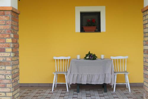 a table with two chairs in front of a yellow wall at Zöld Tanya Vendégház és Rendezvényközpont in Kiskunmajsa