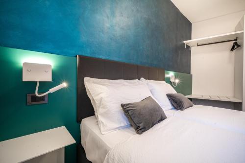 a bedroom with a white bed with a blue wall at Appartamenti Vasco Renna Surf Center in Nago-Torbole