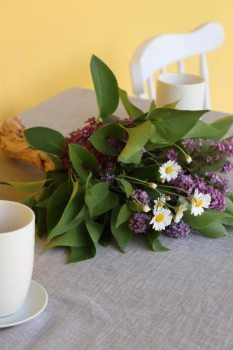 a bouquet of flowers on a table with two cups at Zöld Tanya Vendégház és Rendezvényközpont in Kiskunmajsa