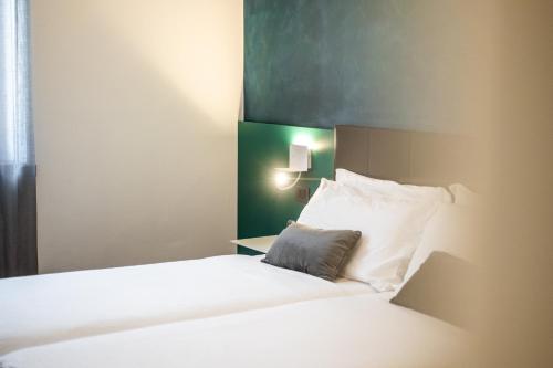 a hotel room with a bed with white pillows at Appartamenti Vasco Renna Surf Center in Nago-Torbole