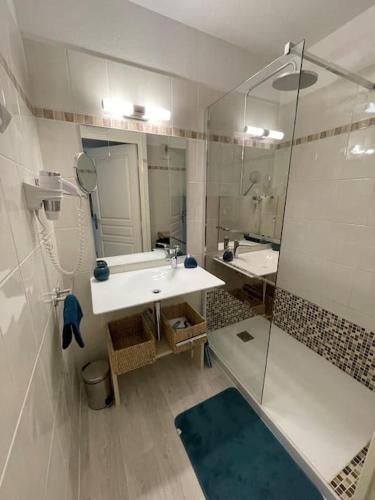 une salle de bain blanche avec un lavabo et une douche dans l'établissement Côte d’Azur- Appartement Les Suites de Robinson, à Mandelieu-la-Napoule