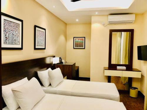 a hotel room with two beds and a television at Tropic Inn - Mount Lavinia in Mount Lavinia