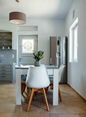 a kitchen with a white table and a white chair at Sea and Sun l in Mylopotas