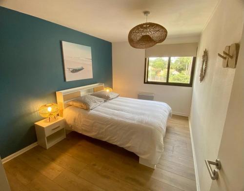 a bedroom with a white bed and a window at Blue ocean in Biscarrosse