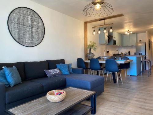 a living room with a blue couch and a kitchen at Blue ocean in Biscarrosse