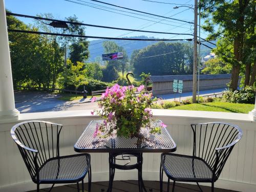a table with a vase of flowers on a porch at The Stowe Village Inn in Stowe