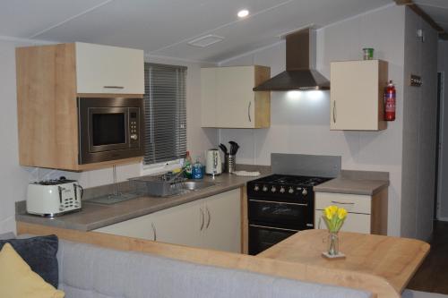 a kitchen with a table and a stove top oven at Holiday Home at Cherry Tree Holiday Park 738 in Great Yarmouth