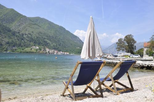 two chairs sitting on a beach with an umbrella at Apartments Vujošević in Kotor