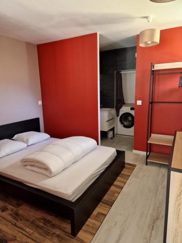 a bedroom with two beds and a red wall at STUDIO 2 chez Fred et Val in Embrun