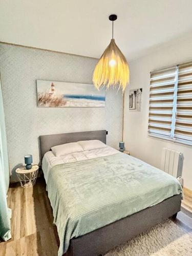 une chambre avec un lit et un lustre dans l'établissement Maison Coquelicots - 4 personnes - jardin, à Mornac-sur-Seudre