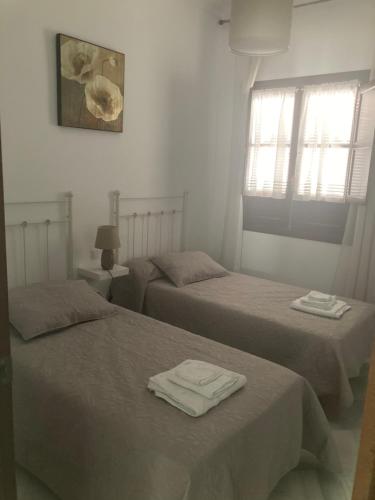 two beds in a white room with towels on them at Duplex Santamaria in Carmona