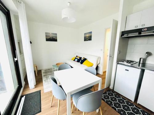 - une cuisine avec une table et des chaises blanches dans la chambre dans l'établissement Studio cosy au calme à 5 min de la plage, à Camiers