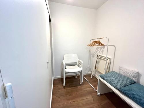 a white room with a chair and a mirror at Studio cosy au calme à 5 min de la plage in Camiers