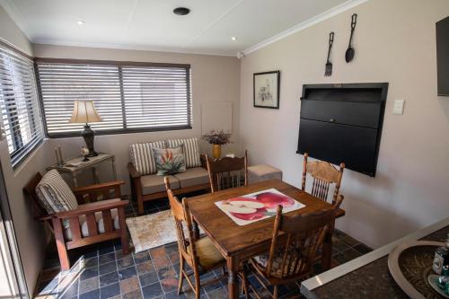 een woonkamer met een tafel en stoelen en een televisie bij SUMMER PLACE in Harrismith