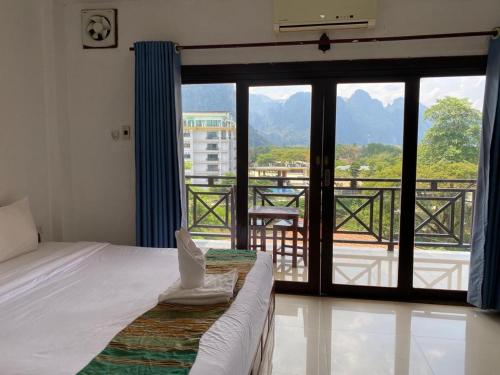 a bedroom with a bed and a view of a balcony at Lisha The Grand Riverside Hotel in Vang Vieng