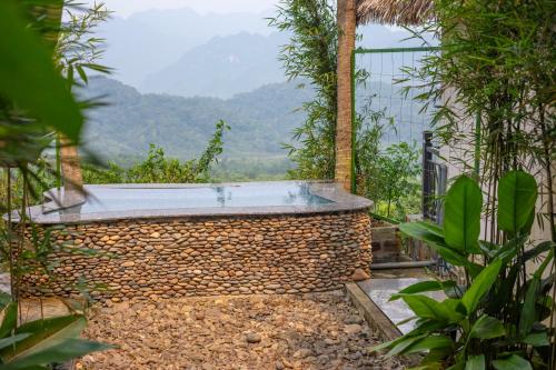 a hot tub in a garden with mountains in the background at EBINO PULUONG RESORT and SPA in Pu Luong